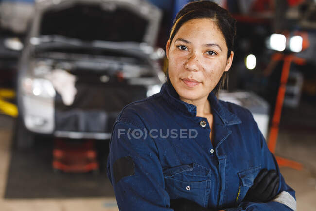 Mécanicien automobile mixte féminin en salopette, regardant la caméra. propriétaire d'entreprise indépendant au garage d'entretien de voiture. — Photo de stock
