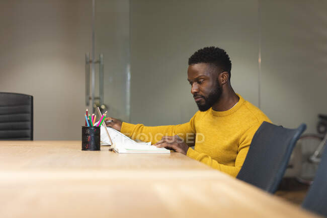 Nachdenkliche afrikanisch-amerikanische Männer, die kreativ am Schreibtisch sitzen und arbeiten. unabhängige kreative Geschäftsleute, die in einem modernen Büro arbeiten. — Stockfoto