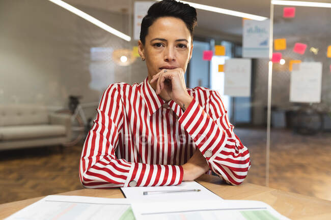 Ernsthafte kaukasische Unternehmerinnen sitzen am Schreibtisch und schauen in die Kamera. unabhängige kreative Geschäftsleute, die in einem modernen Büro arbeiten. — Stockfoto