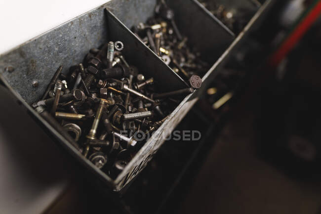 Close up of containers full of screws and nuts. independent business owner at car servicing garage. — Stock Photo