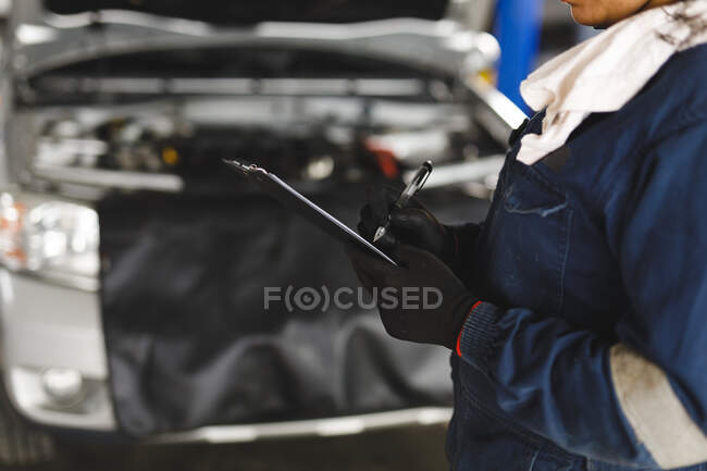 Hände einer Automechanikerin in Overalls, die Notizen macht. Selbstständiger Unternehmer in der Kfz-Werkstatt. — Stockfoto