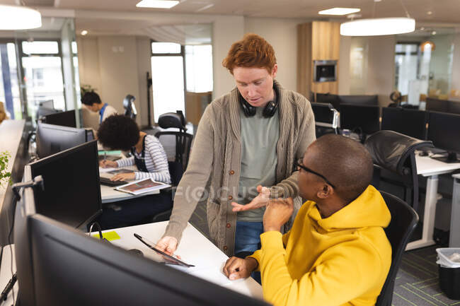 Divers collègues masculins et féminins au travail, assis au bureau, parlant. travailler dans une entreprise créative dans un bureau moderne. — Photo de stock