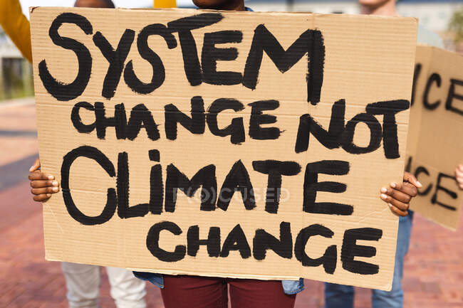 African american woman holding placard saying system change not climate change at protest march. equal rights and justice protestors on demonstration march. — Stock Photo