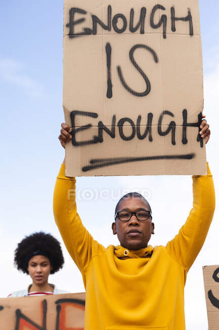 African american man holding placard saying enough is enough at protest march. equal rights and justice protestors on demonstration march. — Stock Photo