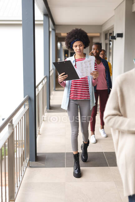 Diverse male and female colleagues at work, walking, holding folders. working in creative business at a modern office. — Stock Photo