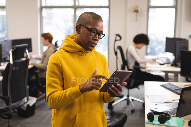 Homme afro-américain créatif au travail, en utilisant une tablette. travailler dans une entreprise créative dans un bureau moderne. — Photo de stock
