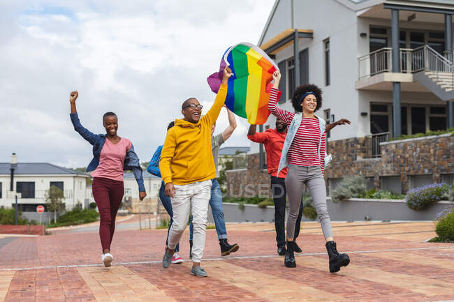 Smiling diverse group of people holding lgbt flag at protest march. equal rights and justice protestors on demonstration march. — Stock Photo
