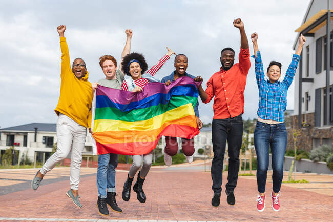 Lächelnde Gruppe von Menschen mit lgbt-Flagge beim Protestmarsch. Demonstranten für gleiche Rechte und Gerechtigkeit auf Demonstrationszug. — Stockfoto