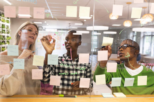 Diverse männliche und weibliche Kollegen arbeiten zusammen, Brainstorming, schreiben an Notizen. Arbeit im kreativen Geschäft in einem modernen Büro. — Stockfoto