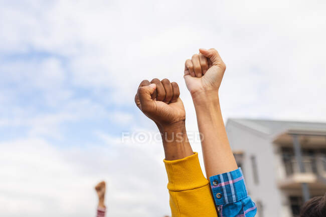 Diversas personas levantando los puños en una marcha de protesta. manifestantes por la igualdad de derechos y justicia en marcha. - foto de stock