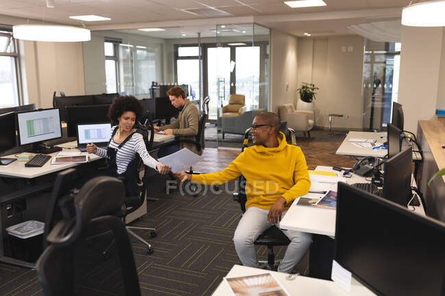 Різні чоловіки і жінки-колеги на роботі, сидячи за столами, використовуючи комп'ютери. робота в креативному бізнесі в сучасному офісі . — стокове фото