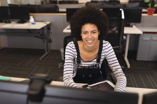 Lächelnde Mischlingshündin bei der Arbeit, am Schreibtisch, am Computer. Arbeit im kreativen Geschäft in einem modernen Büro. — Stockfoto