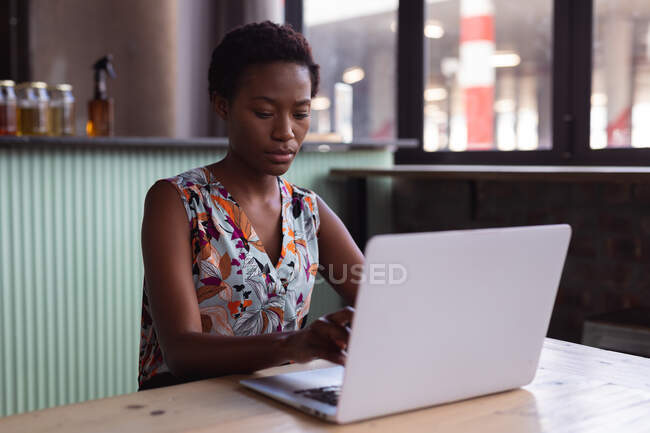 Mulher americana africana cuidadosa usando laptop na destilaria gin. conceito de negócio de destilaria artesanal independente — Fotografia de Stock