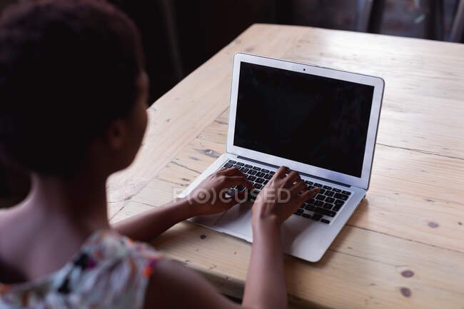 Visão traseira da mulher afro-americana usando laptop na destilaria gin. conceito de negócio de destilaria artesanal independente — Fotografia de Stock