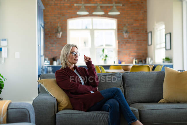 Mulher caucasiana sênior pensativo na sala de estar sentado no sofá, pensando. estilo de vida da aposentadoria, passar tempo em casa. — Fotografia de Stock