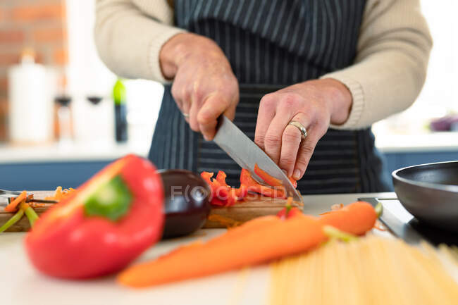Close up of woman in kitchen wearing apron cooking. healthy, active retirement lifestyle at home. — Stock Photo