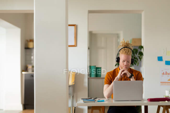 Homme afro-américain albinos avec dreadlocks travailler de la maison et faire appel vidéo sur l'ordinateur portable. télétravail utilisant la technologie à la maison. — Photo de stock