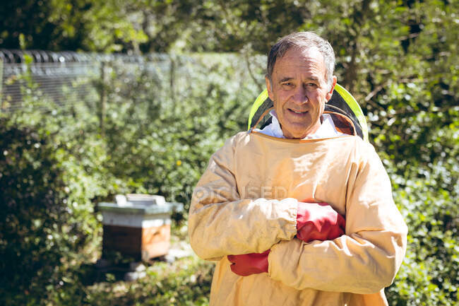 Старший белый мужчина в пчеловодческой форме и смотрит в камеру. пчеловодство, пасека и мёд. — стоковое фото