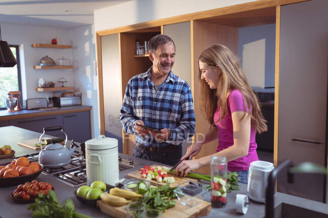 Happy caucasian grandfather and granddaughter preparing smoothie in kitchen. active and healthy retirement lifestyle at home. — Stock Photo
