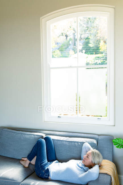 Relaxed senior caucasian woman in living room lying on sofa. retirement lifestyle, spending time at home. — Stock Photo