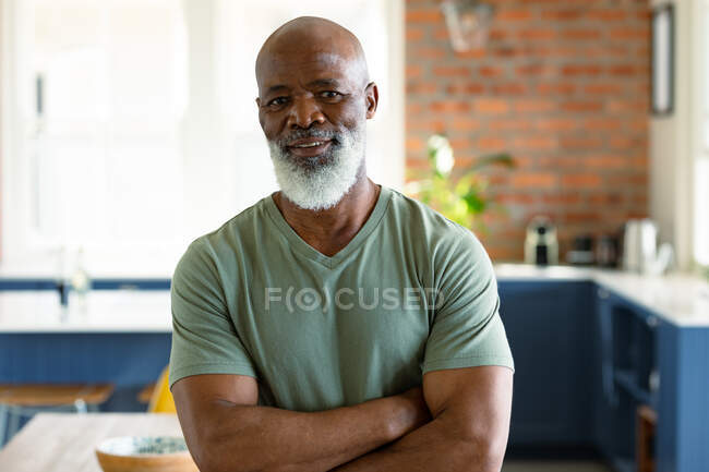 Retrato del hombre afroamericano mayor feliz en la cocina mirando a la cámara. estilo de vida de jubilación, pasar tiempo en casa. - foto de stock