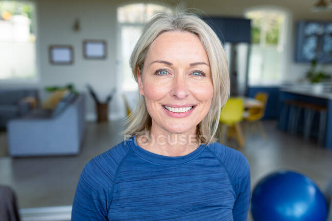 Портрет щасливої старшої жінки, яка займається фізичними вправами, дивиться на камеру і посміхається. Здоровий, активний спосіб життя вдома. — стокове фото