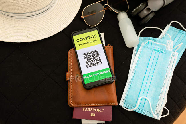 Smartphone com covid 19 passaporte da vacina, máscaras faciais e líquido desinfetante. preparação para férias e viagens durante a pandemia de 19 pessoas. — Fotografia de Stock
