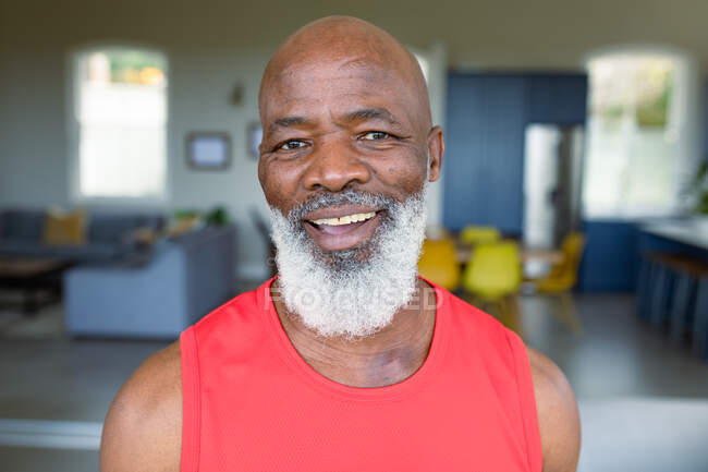 Retrato de homem americano africano sênior feliz em roupas de exercício olhando para a câmera e sorrindo. estilo de vida saudável e ativo em casa. — Fotografia de Stock