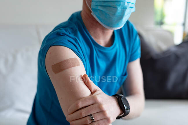 Primo piano dell'uomo albino afro-americano che indossa una maschera facciale con intonaco dopo la vaccinazione. Global Covid 19 pandemia e assistenza sanitaria. — Foto stock