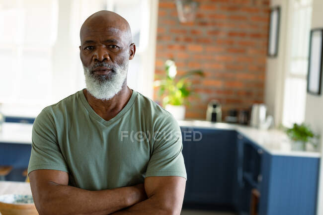 Ritratto di uomo anziano afroamericano pensieroso in cucina che guarda la macchina fotografica. stile di vita di pensione, trascorrere del tempo a casa. — Foto stock