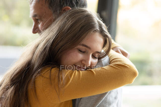 Glücklicher kaukasischer Großvater und Enkelin, die sich zu Hause umarmen. Familienzeit, aktiver und gesunder Lebensstil im Ruhestand zu Hause. — Stockfoto