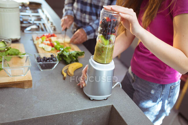 Midsection of grandfather and granddaughter preparing smoothie in kitchen. active and healthy retirement lifestyle at home. — Stock Photo