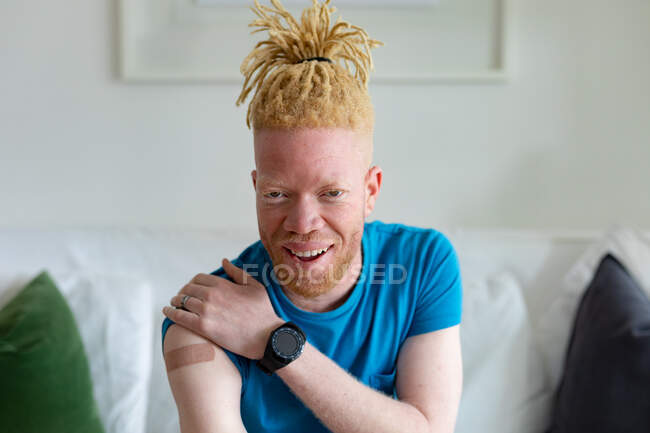 Feliz hombre albino afroamericano con yeso después de la vacunación. mundial covid 19 pandemia y atención sanitaria. - foto de stock
