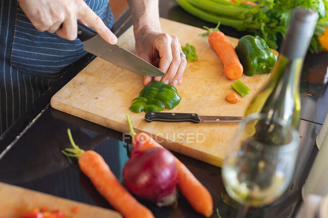 Primo piano dell'uomo che prepara un pasto e taglia le verdure sul tavolo della cucina. godendo del tempo libero a casa. — Foto stock