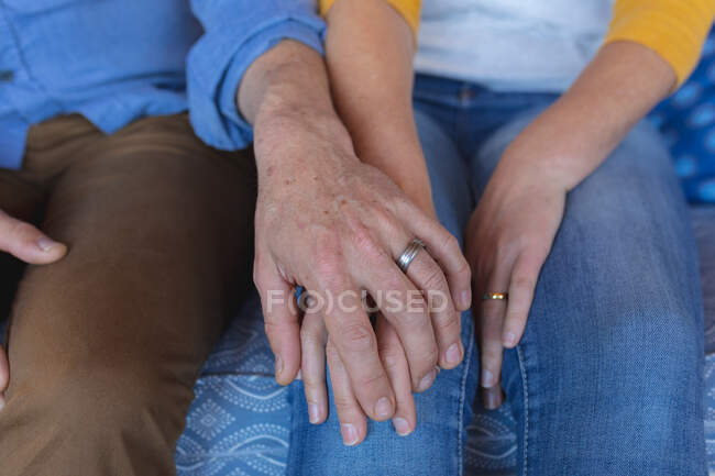 Closeup of caucasian mature couple holding hands with wedding rings. enjoying leisure time at home. — Stock Photo