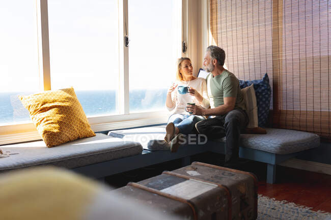 Feliz casal maduro caucasiano bebendo café na sala de estar. desfrutar de tempo de lazer em casa. — Fotografia de Stock