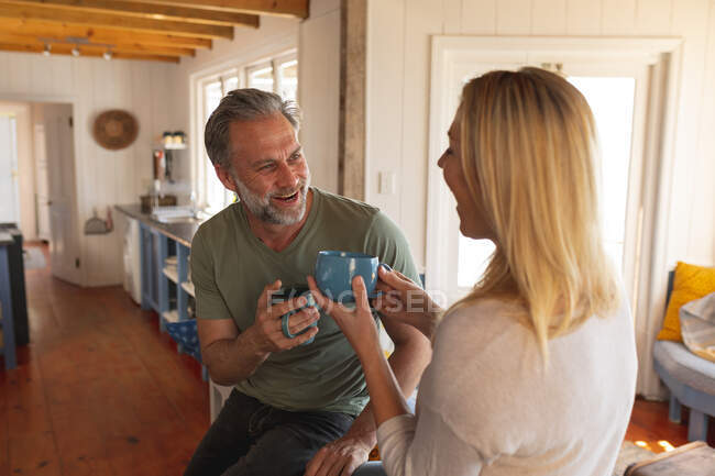 Feliz casal maduro caucasiano bebendo café na cozinha ensolarada. desfrutar de tempo de lazer em casa. — Fotografia de Stock