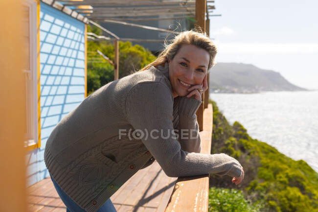 Glückliche kaukasische Frau auf einer Terrasse am Meer. Freizeit am Strand genießen. — Stockfoto
