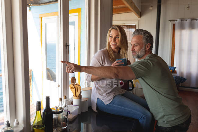 Feliz casal maduro caucasiano bebendo café na cozinha ensolarada. desfrutar de tempo de lazer em casa. — Fotografia de Stock