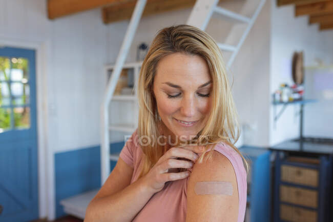 Lächelnde Kaukasierin mit Gips auf dem Arm, wo sie gegen Coronavirus geimpft wurden. Gesundheit und Lebensstil während der Covid 19 Pandemie. — Stockfoto