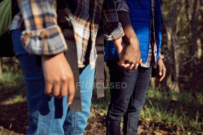 Close up of diverse couple holding hands in countryside. healthy, active outdoor lifestyle and leisure time. — Stock Photo