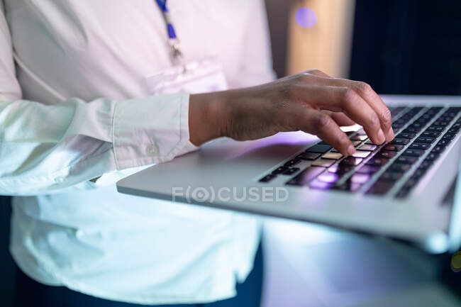 Closeup of african american female computer technician using laptop working in server room. digital information storage and communication network technology. — Stock Photo