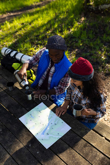 Diverse couple drinking coffee and taking break from hiking in countryside. healthy, active outdoor lifestyle and leisure time. — Stock Photo