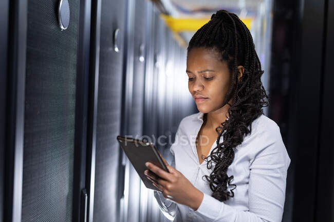 Африканський американський технік-комп'ютерник використовує планшет, що працює в серверній кімнаті. Digital information storage and communication network technique. — стокове фото