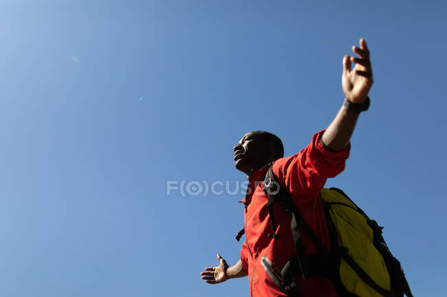 Uomo afroamericano con zaino in piedi a braccia aperte. stile di vita all'aperto sano e attivo e tempo libero. — Foto stock