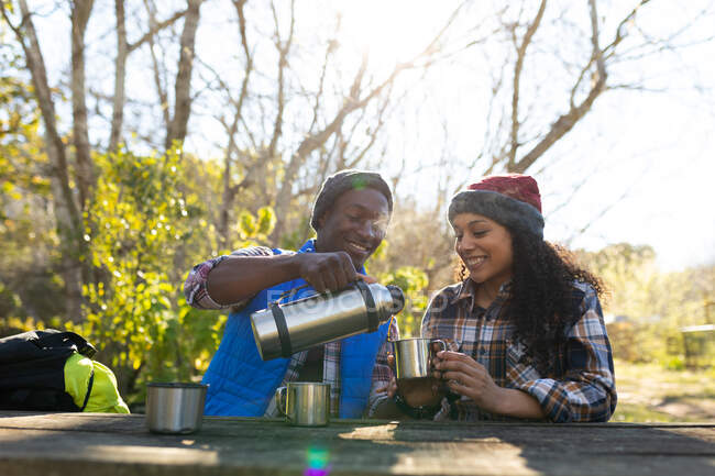 Разнообразная пара пьет кофе и отдыхает от походов в сельской местности. здоровый, активный уличный образ жизни и досуг. — стоковое фото