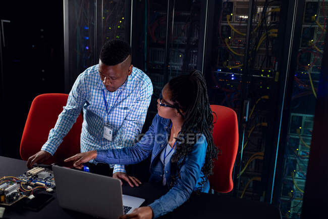 African american computer technicians using laptop working in server room. digital information storage and communication network technology. — Stock Photo