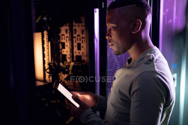 Africano americano técnico de informática do sexo masculino usando tablet e trabalhando na sala de servidores. armazenamento digital de informações e tecnologia de rede de comunicação. — Fotografia de Stock