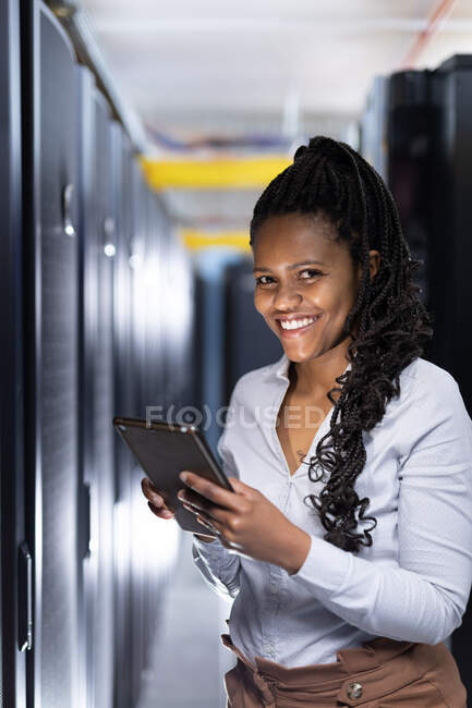 Técnica de informática afro-americana usando tablet trabalhando na sala de servidores. armazenamento digital de informações e tecnologia de rede de comunicação. — Fotografia de Stock
