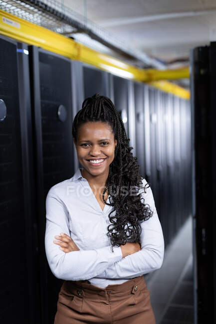 Retrato de una mujer afroamericana que trabaja en la sala de servidores. tecnología de redes digitales de almacenamiento y comunicación de información. - foto de stock